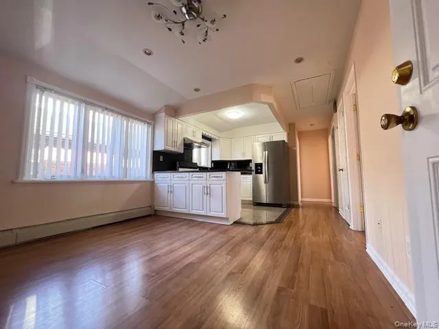 Kitchen featuring baseboard heating, stainless steel fridge, white cabinets, and light wood-type flooring Kitchen featuring baseboard heating, stainless steel fridge, white cabinets, and light wood-type flooring