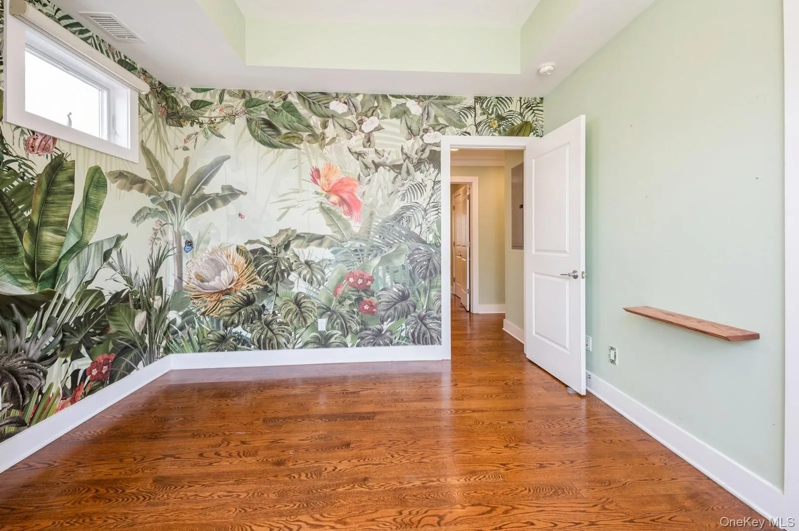 Spare room with baseboards, wallpapered walls, and wood finished floors Spare room with baseboards, wallpapered walls, and wood finished floors