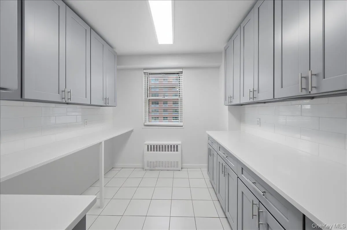 Kitchen (with potential for small breakfast bar) with radiator heating unit and light tile patterned flooring Kitchen (with potential for small breakfast bar) with radiator heating unit and light tile patterned flooring