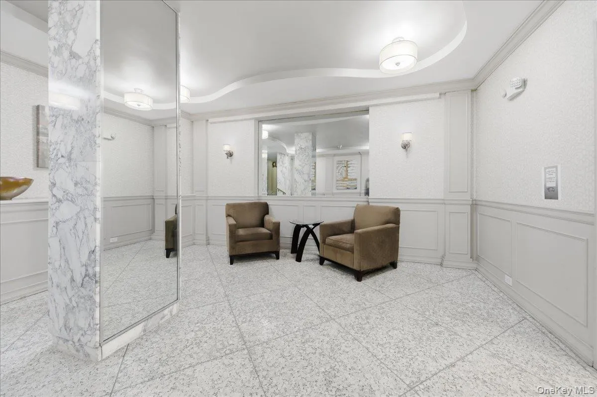Community lobby featuring a decorative wall, a tray ceiling, a wainscoted wall, and ornamental molding Community lobby featuring a decorative wall, a tray ceiling, a wainscoted wall, and ornamental molding