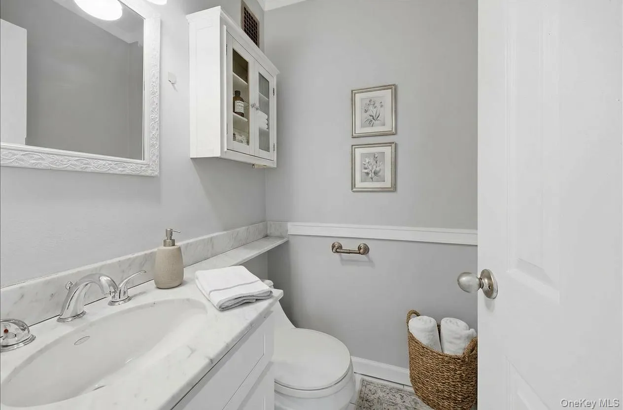 Primary ensuite half bathroom featuring vanity and toilet. Primary ensuite half bathroom featuring vanity and toilet.