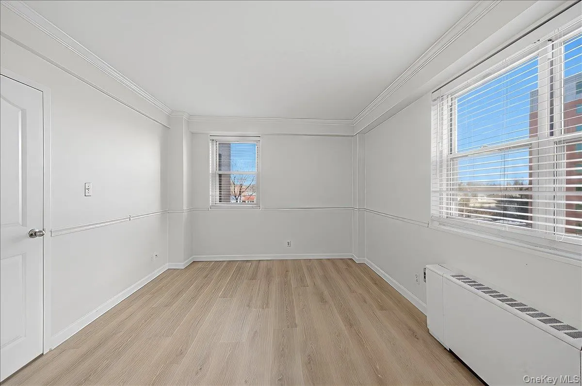 Primary Bedroom featuring radiator heating unit and light wood finished floors Primary Bedroom featuring radiator heating unit and light wood finished floors