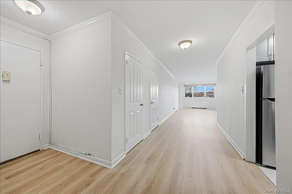 Hall featuring ornamental molding and light wood-style flooring Hall featuring ornamental molding and light wood-style flooring