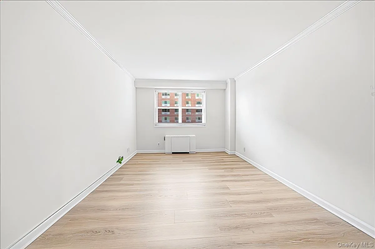 Bedroom with light wood finished floors, radiator, and ornamental molding Bedroom with light wood finished floors, radiator, and ornamental molding
