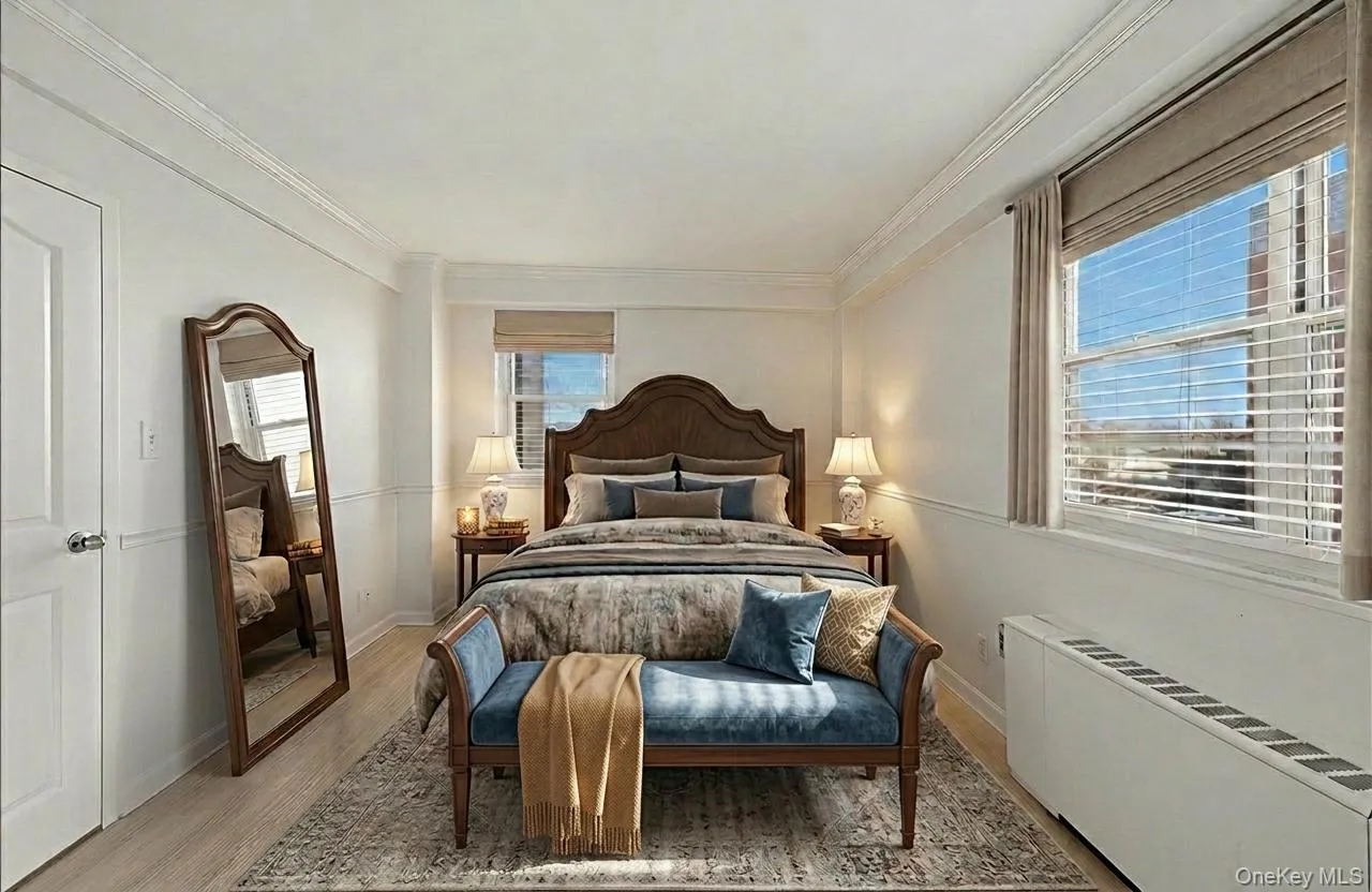 Staged primary bedroom featuring radiator heating unit, light wood-type flooring, and crown molding Staged primary bedroom featuring radiator heating unit, light wood-type flooring, and crown molding