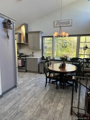 Dining room featuring suspended lighting, light wood-type flooring, and vaulted ceiling Dining room featuring suspended lighting, light wood-type flooring, and vaulted ceiling