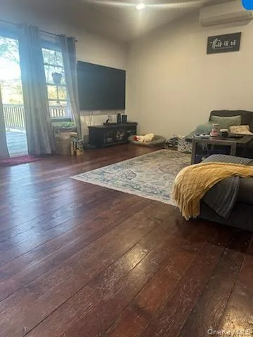 Living room with dark wood-style flooring and a wall mounted AC Living room with dark wood-style flooring and a wall mounted AC