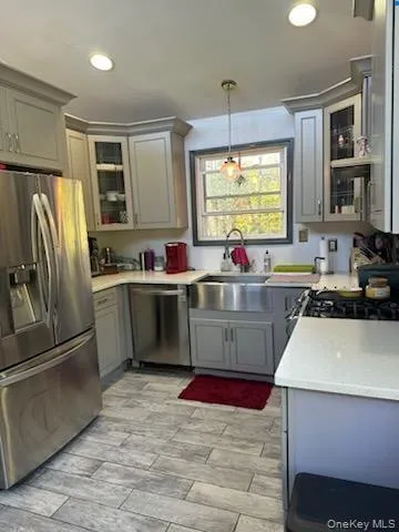 Kitchen featuring glass insert cabinets, gray cabinets, stainless steel appliances, and hanging light fixtures Kitchen featuring glass insert cabinets, gray cabinets, stainless steel appliances, and hanging light fixtures