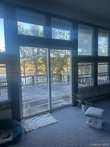 Doorway to outside featuring carpet and a high ceiling Doorway to outside featuring carpet and a high ceiling