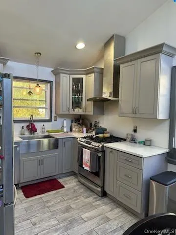 Kitchen featuring gray cabinets, stainless steel appliances, light countertops, decorative light fixtures, and glass fronted cabinets Kitchen featuring gray cabinets, stainless steel appliances, light countertops, decorative light fixtures, and glass fronted cabinets