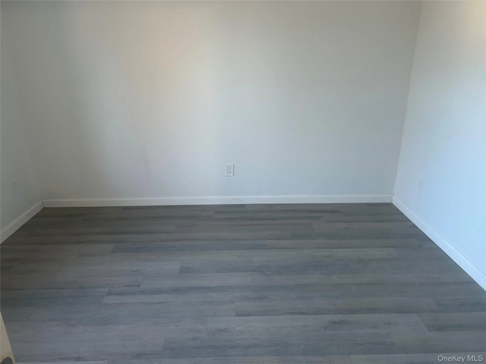 Spare room featuring dark wood-style flooring and baseboards Spare room featuring dark wood-style flooring and baseboards