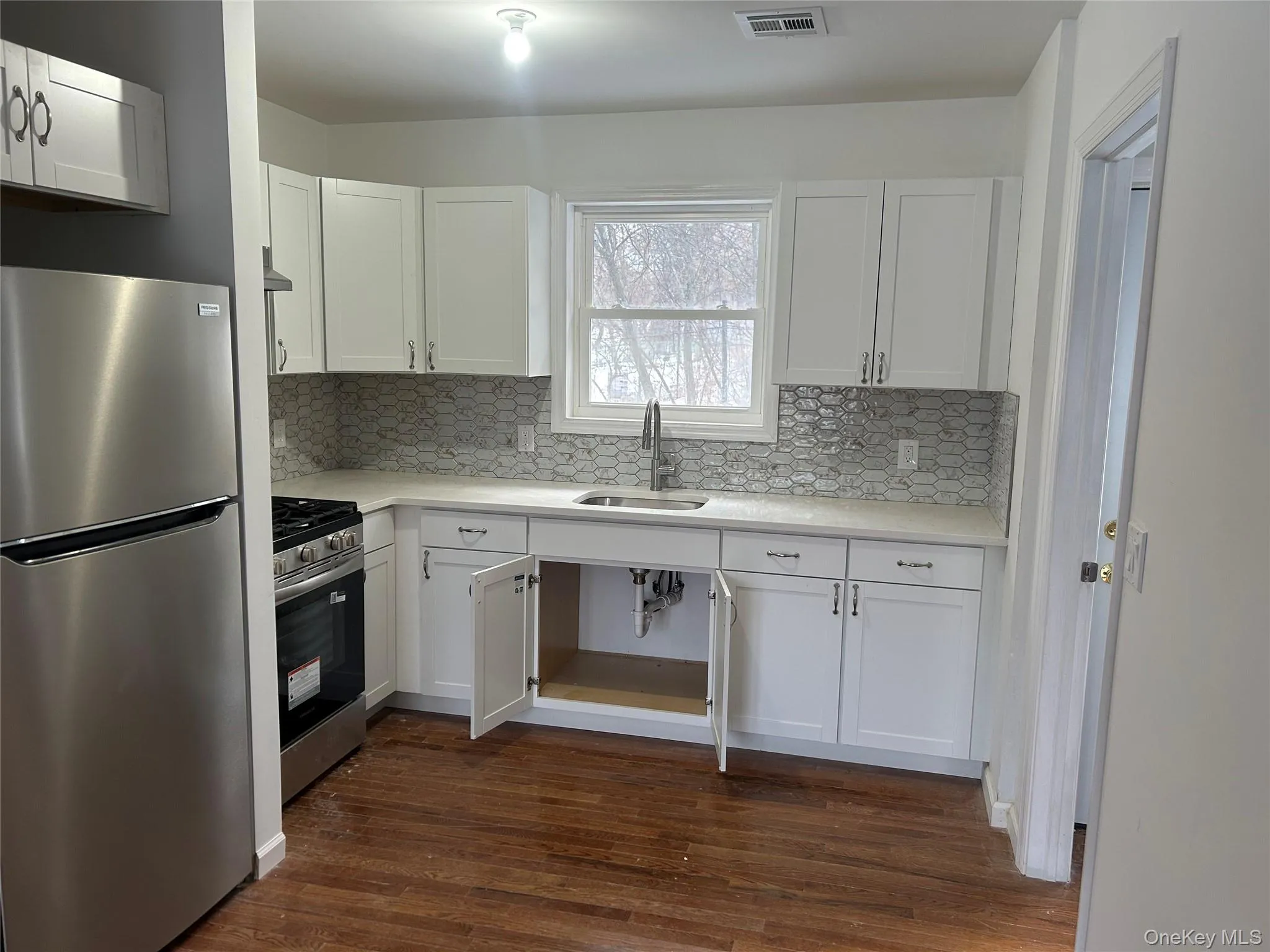 Kitchen with #2 appliances with stainless steel finishes, white cabinetry, and decorative backsplash Kitchen with #2 appliances with stainless steel finishes, white cabinetry, and decorative backsplash