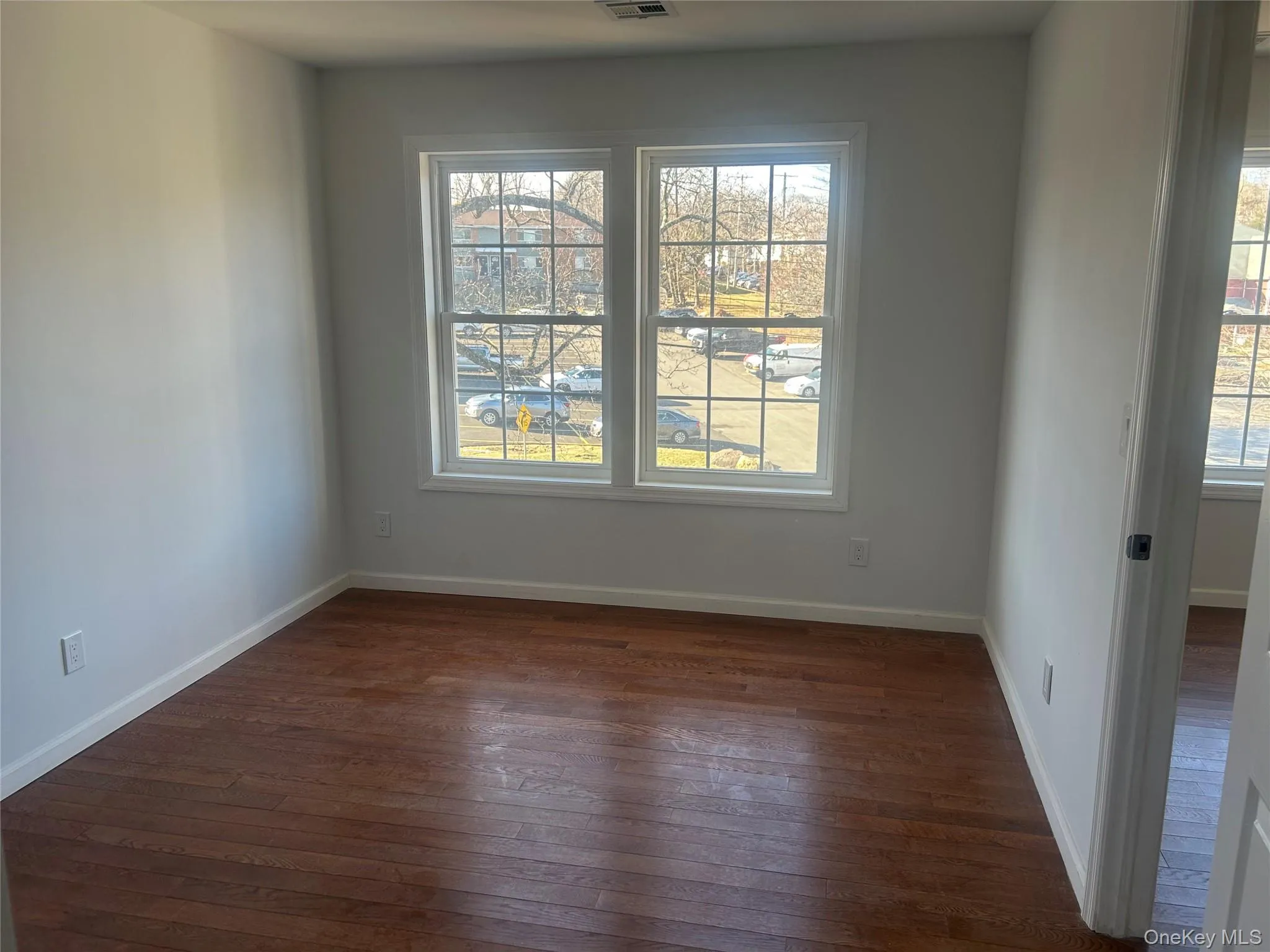 Spare room with dark wood-type flooring and baseboards Spare room with dark wood-type flooring and baseboards