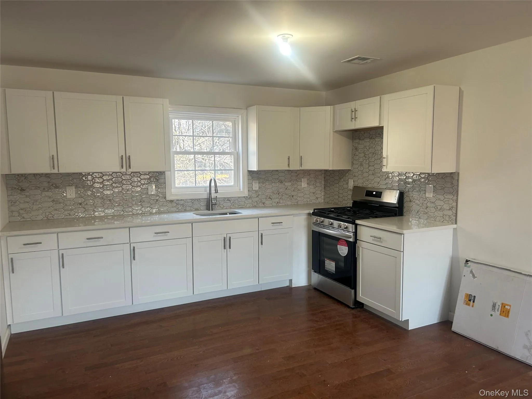 Kitchen# 1 featuring stainless steel range with gas stovetop, white cabinets, dark wood-style flooring, and backsplash Kitchen# 1 featuring stainless steel range with gas stovetop, white cabinets, dark wood-style flooring, and backsplash