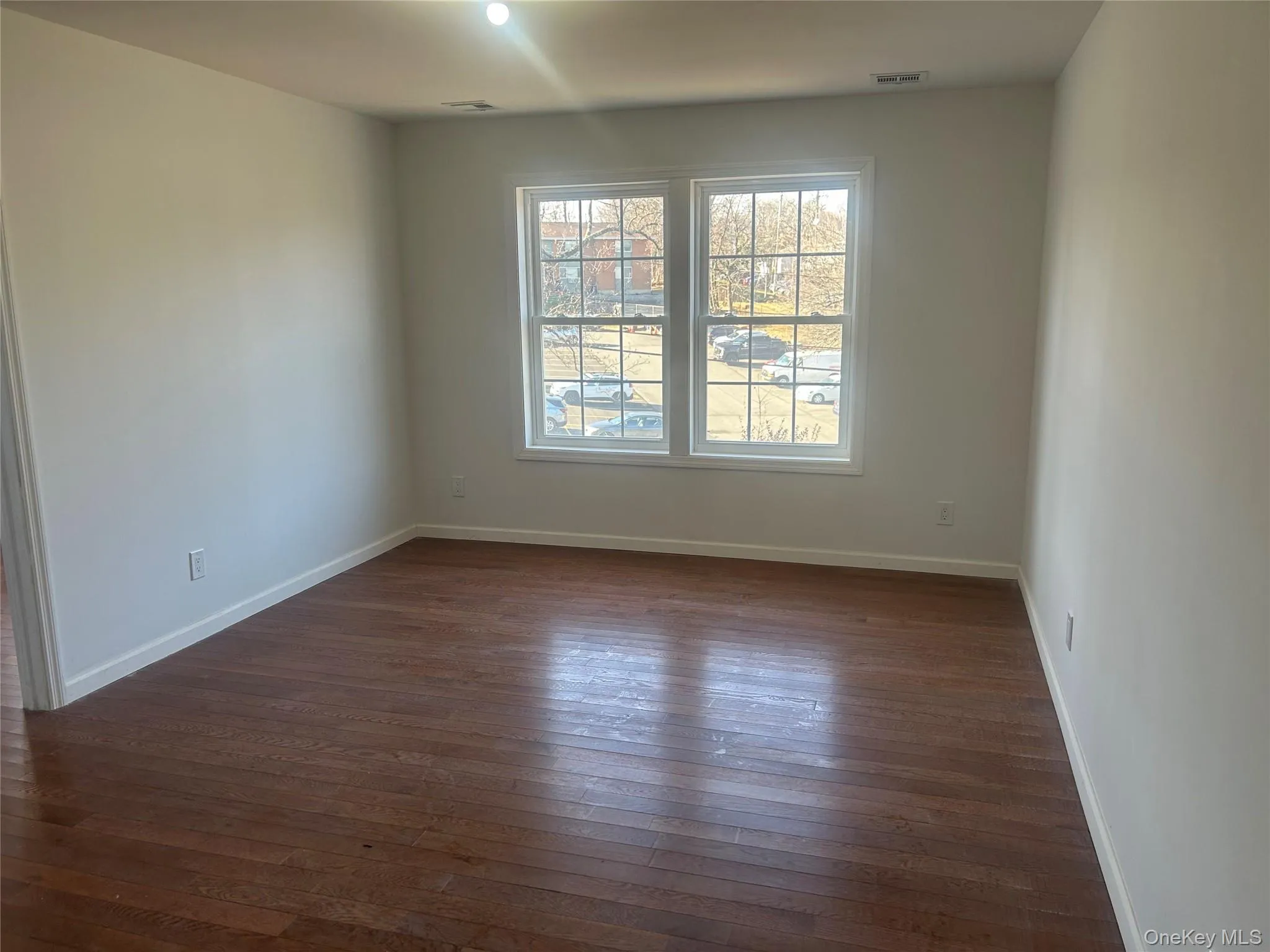 Unfurnished room with dark wood-style flooring and baseboards Unfurnished room with dark wood-style flooring and baseboards