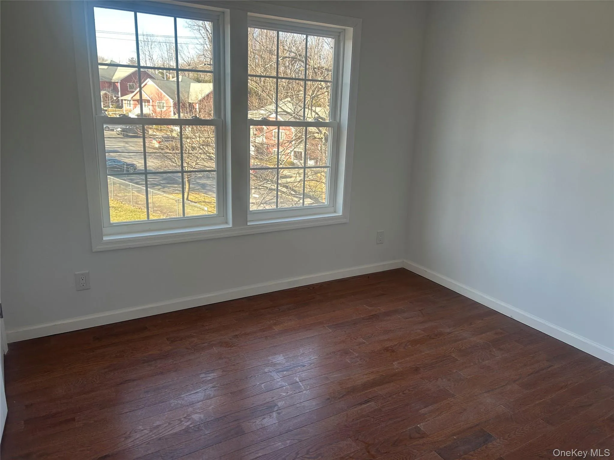 Unfurnished room featuring dark wood-style floors and plenty of natural light Unfurnished room featuring dark wood-style floors and plenty of natural light