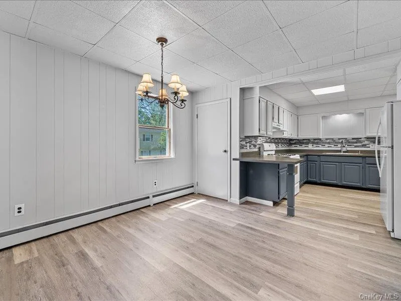 Kitchen with gas range, freestanding refrigerator, baseboard heating, a sink, and a paneled ceiling Kitchen with gas range, freestanding refrigerator, baseboard heating, a sink, and a paneled ceiling