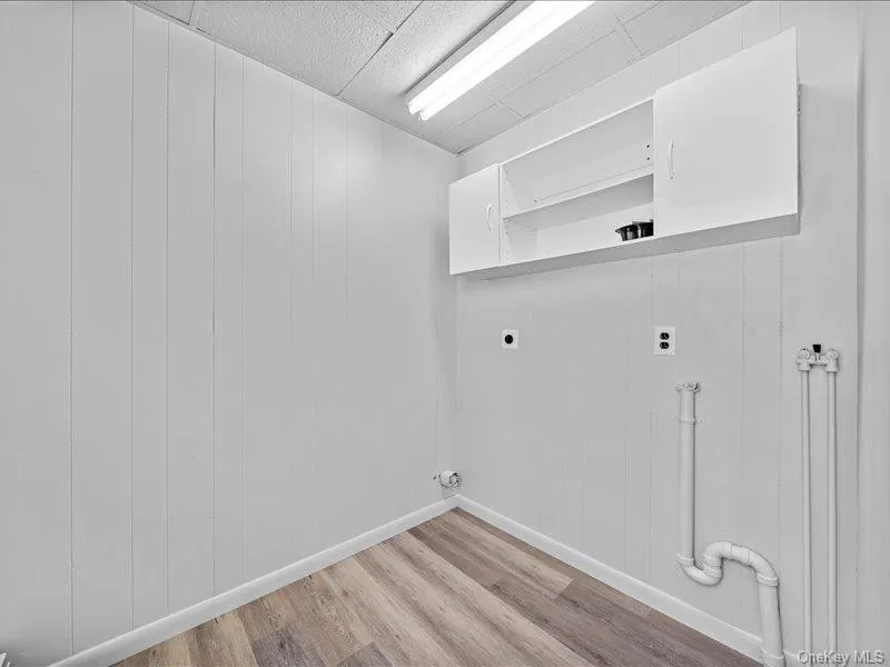 Washroom with hookup for an electric dryer, light wood-style flooring, and baseboards Washroom with hookup for an electric dryer, light wood-style flooring, and baseboards