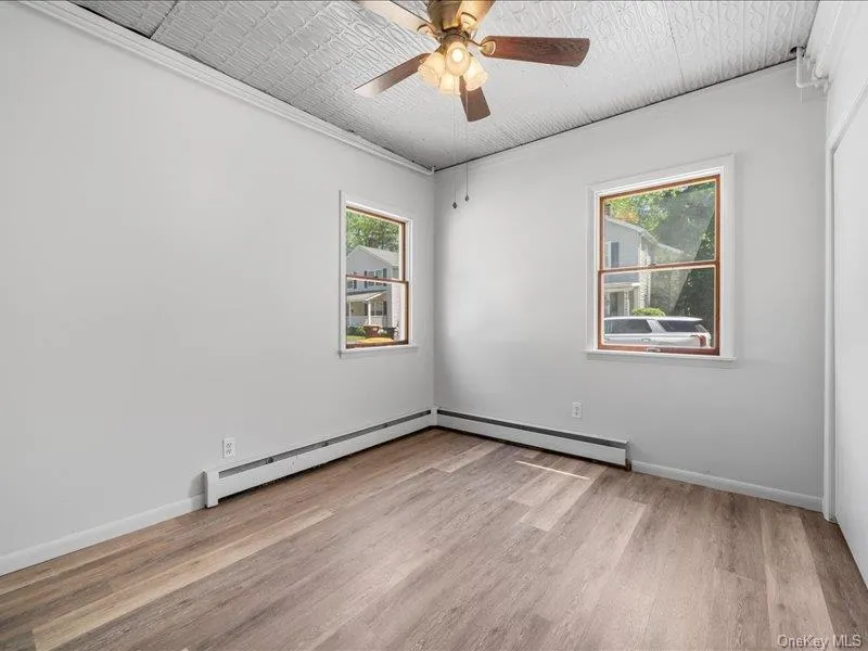 Spare room with a baseboard heating unit, wood finished floors, and baseboards Spare room with a baseboard heating unit, wood finished floors, and baseboards