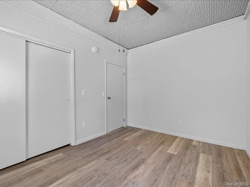 Unfurnished bedroom featuring wood finished floors, an ornate ceiling, ceiling fan, a closet, and crown molding Unfurnished bedroom featuring wood finished floors, an ornate ceiling, ceiling fan, a closet, and crown molding