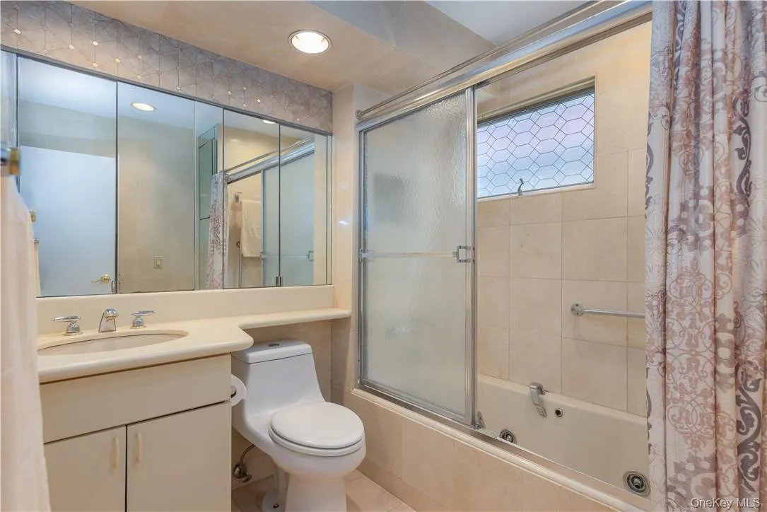 Full bathroom featuring vanity, toilet, tile patterned flooring, and bath / shower combo with glass door Full bathroom featuring vanity, toilet, tile patterned flooring, and bath / shower combo with glass door