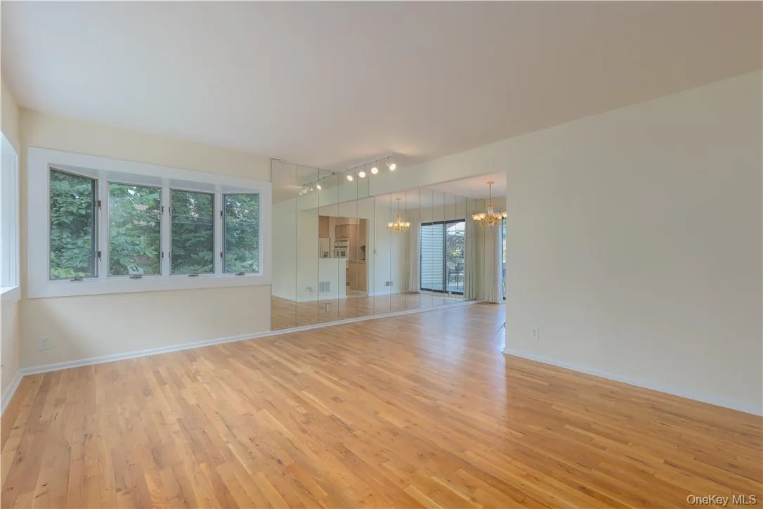 Empty room with a chandelier, a healthy amount of sunlight, rail lighting, and light wood-type flooring Empty room with a chandelier, a healthy amount of sunlight, rail lighting, and light wood-type flooring