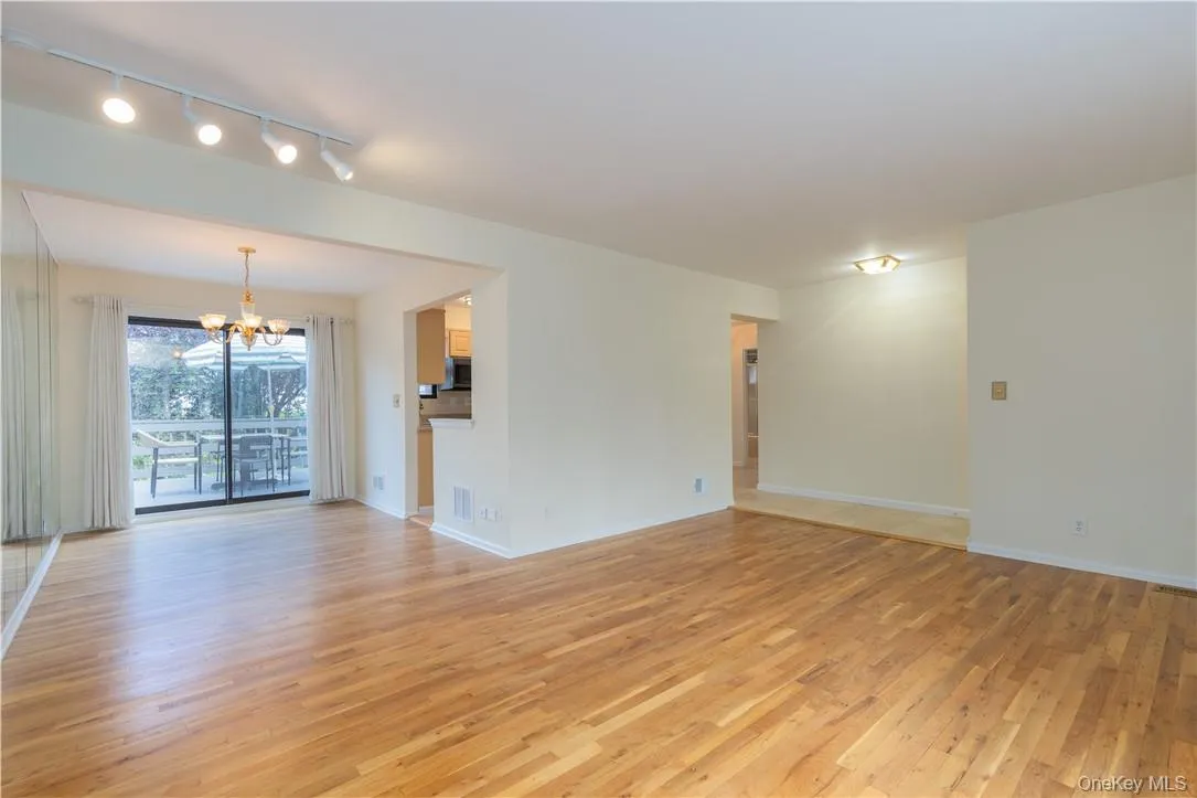 Unfurnished living room featuring light hardwood / wood-style flooring, rail lighting, and a chandelier Unfurnished living room featuring light hardwood / wood-style flooring, rail lighting, and a chandelier