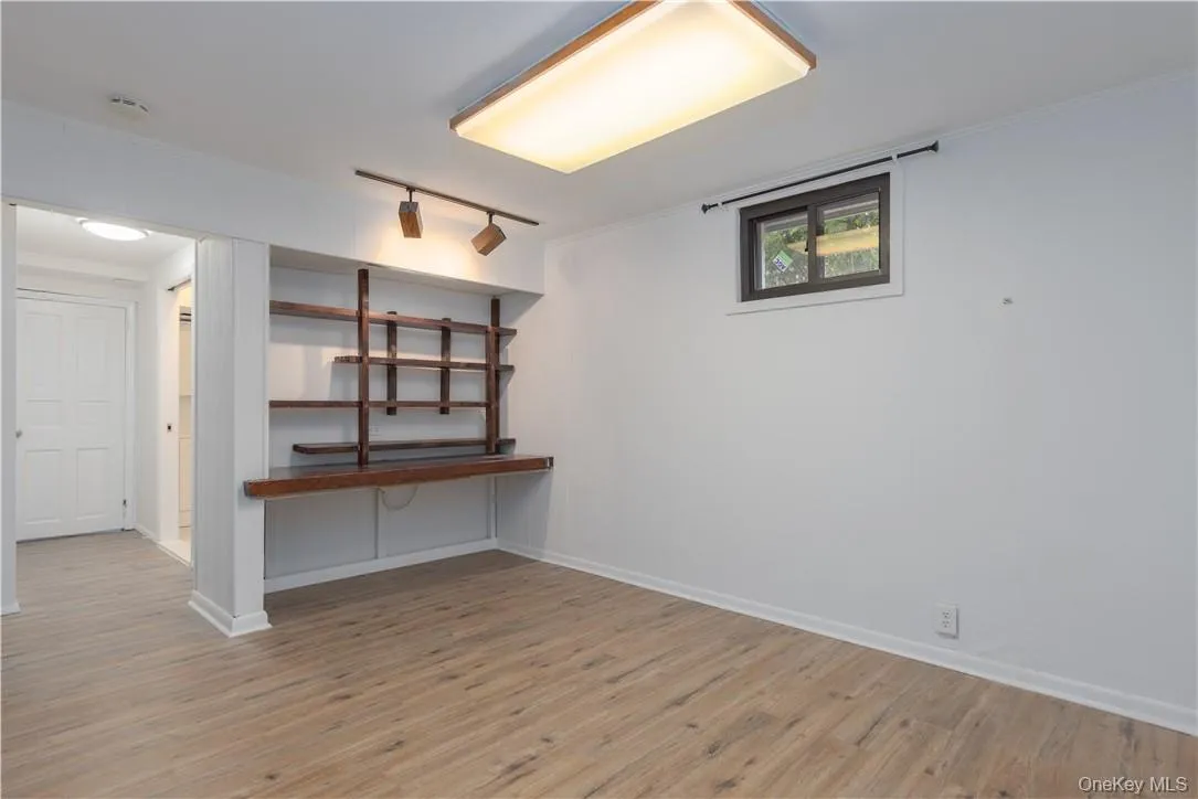 Basement with crown molding, rail lighting, and light hardwood / wood-style flooring Basement with crown molding, rail lighting, and light hardwood / wood-style flooring