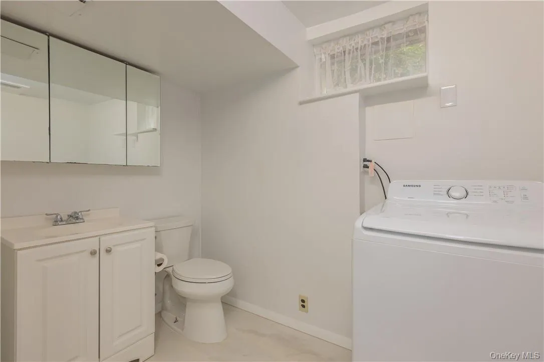 Bathroom with washer / clothes dryer, vanity, tile patterned floors, and toilet Bathroom with washer / clothes dryer, vanity, tile patterned floors, and toilet