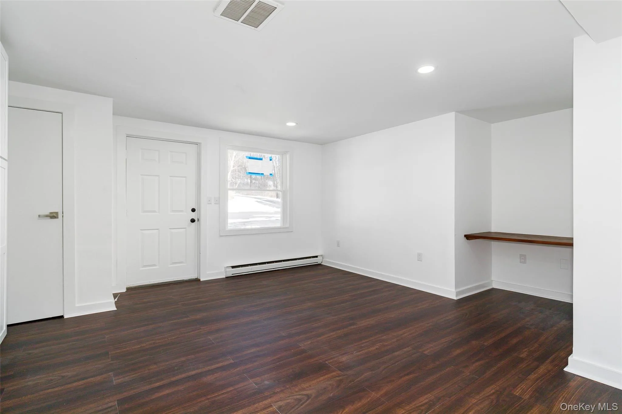 Living room with baseboards, dark wood-style floors, baseboard heating, and recessed lighting Living room with baseboards, dark wood-style floors, baseboard heating, and recessed lighting