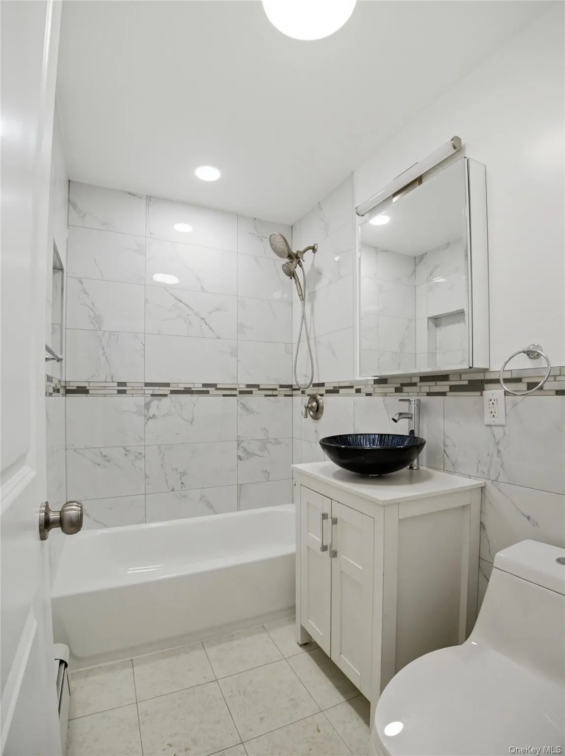 Full bath with vanity, bathing tub / shower combination, tile walls, light tile patterned floors, and recessed lighting Full bath with vanity, bathing tub / shower combination, tile walls, light tile patterned floors, and recessed lighting