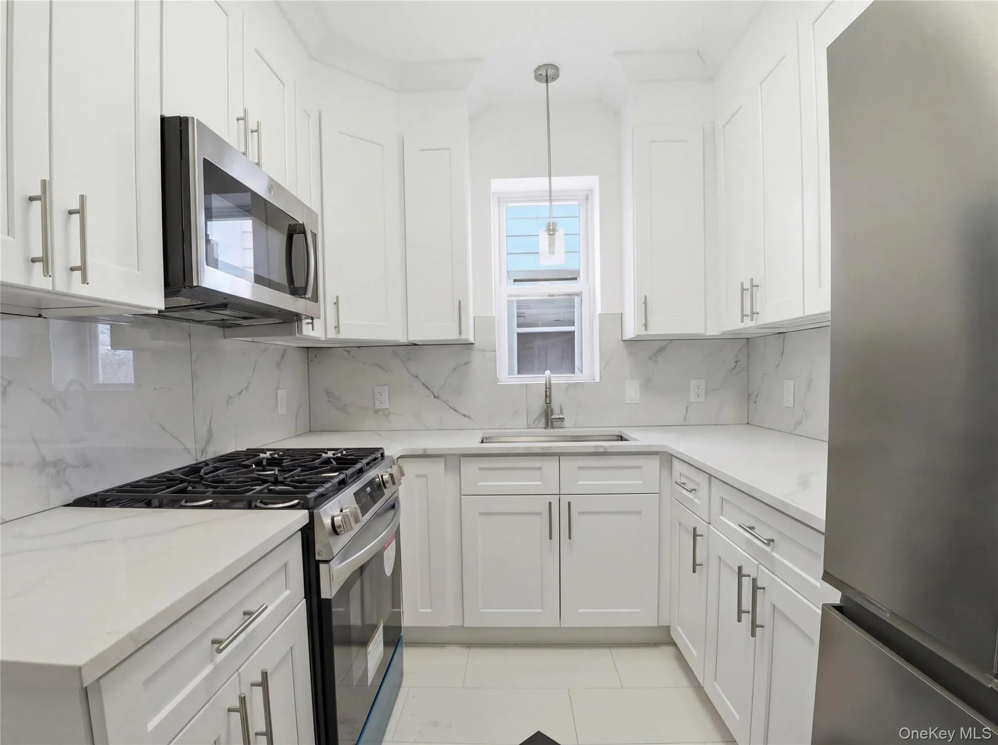 Kitchen featuring stainless steel appliances, white cabinetry, pendant lighting, and light color countertops Kitchen featuring stainless steel appliances, white cabinetry, pendant lighting, and light color countertops