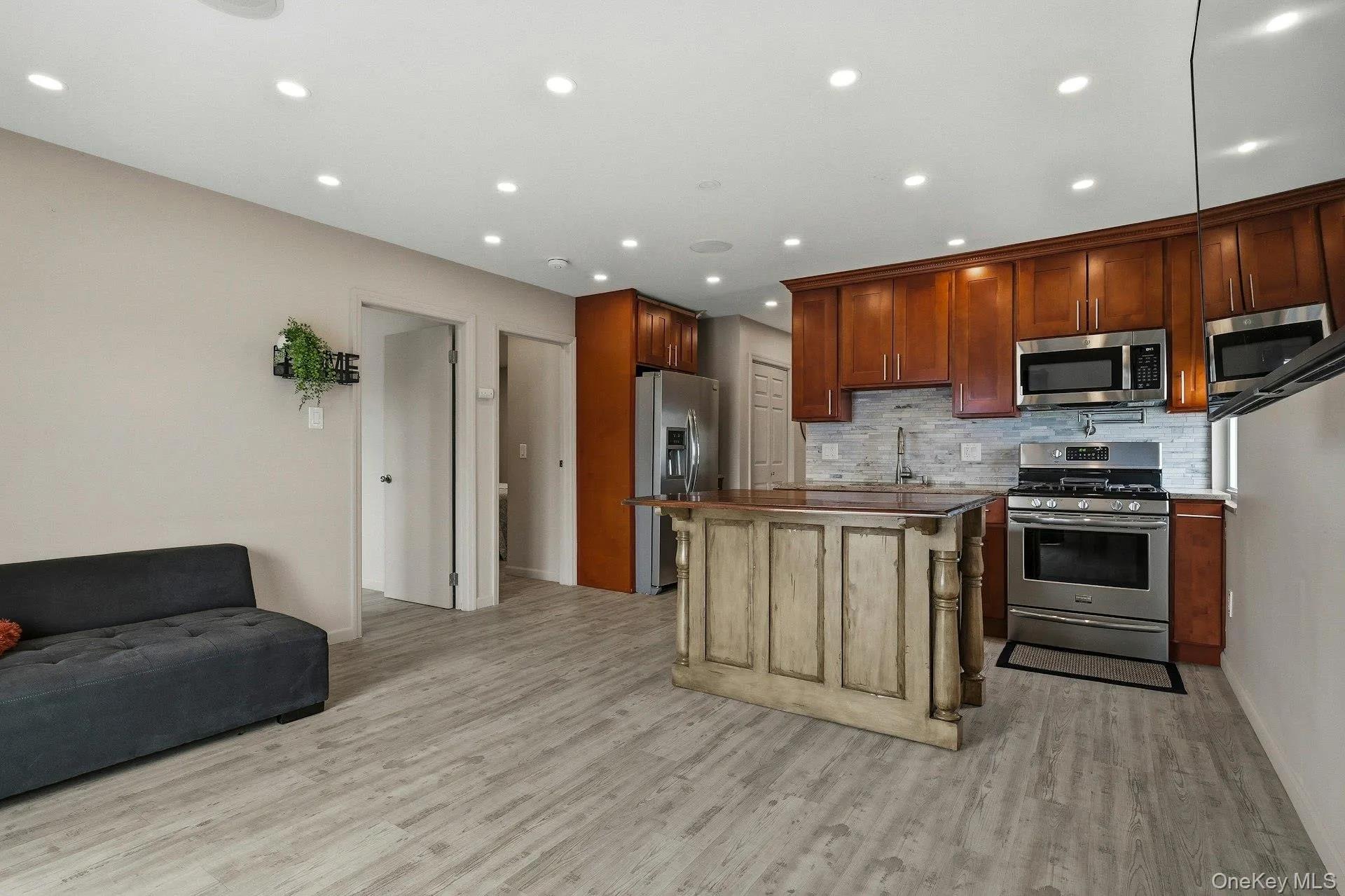 Kitchen featuring stainless steel appliances, a kitchen island, open floor plan, recessed lighting, and light wood-style flooring Kitchen featuring stainless steel appliances, a kitchen island, open floor plan, recessed lighting, and light wood-style flooring