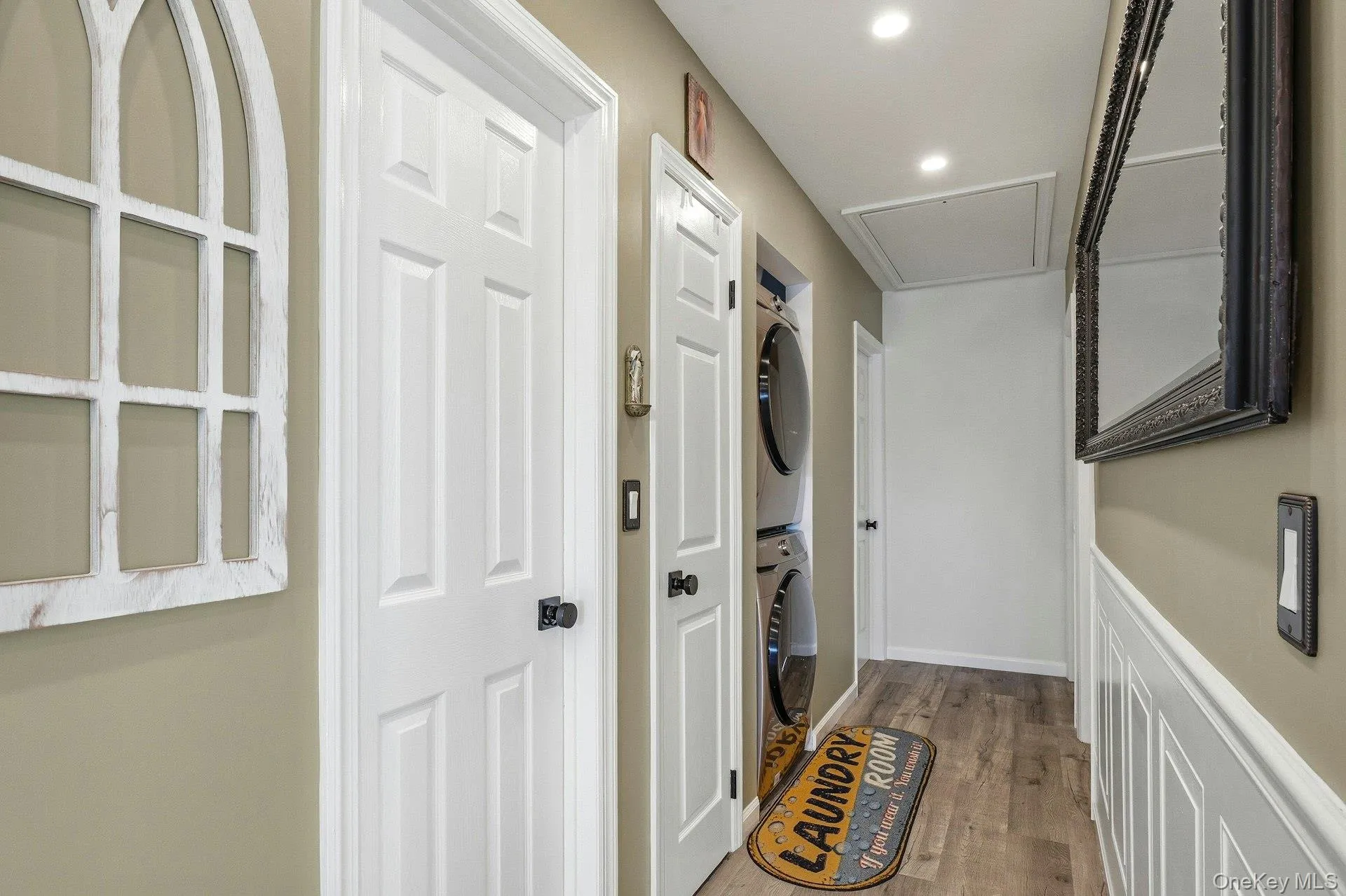 Laundry area featuring light wood finished floors, stacked washer and dryer, and recessed lighting Laundry area featuring light wood finished floors, stacked washer and dryer, and recessed lighting