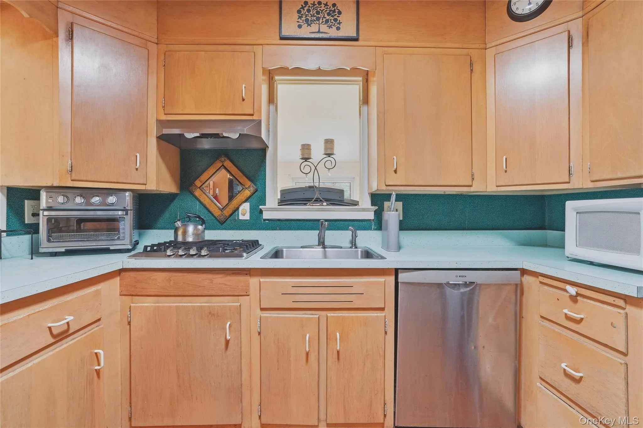 The kitchen features wood cabinetry, a gas cooktop, a stainless steel dishwasher The kitchen features wood cabinetry, a gas cooktop, a stainless steel dishwasher