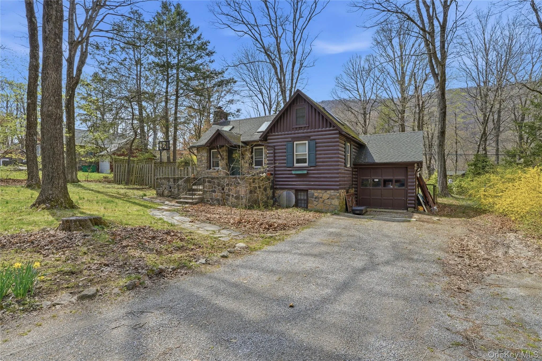 This property features a rustic-style exterior with wood siding and a stone foundation, complemented by a gravel driveway This property features a rustic-style exterior with wood siding and a stone foundation, complemented by a gravel driveway