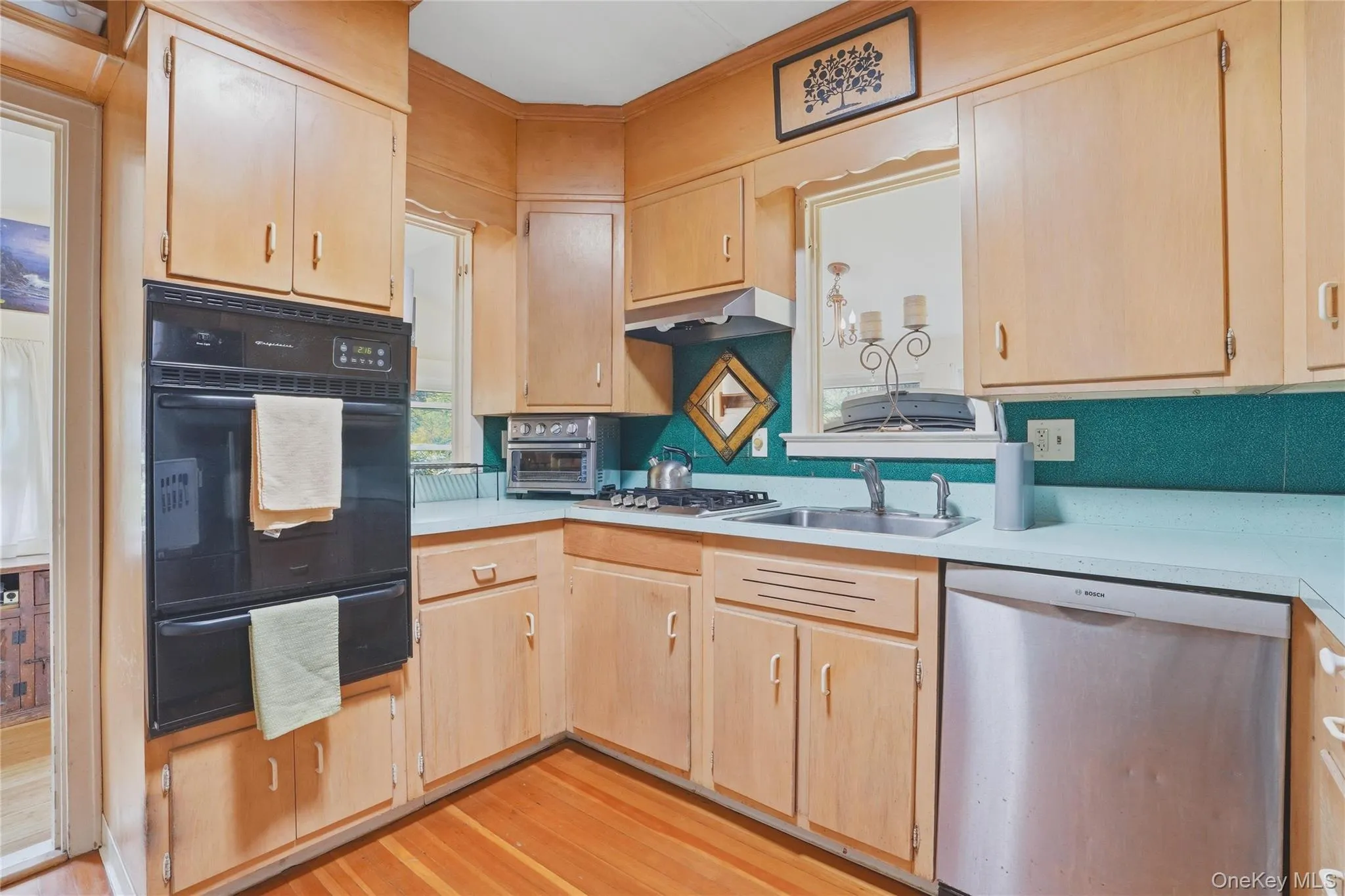 The kitchen features wooden cabinetry, light-colored countertops, and hardwood flooring The kitchen features wooden cabinetry, light-colored countertops, and hardwood flooring