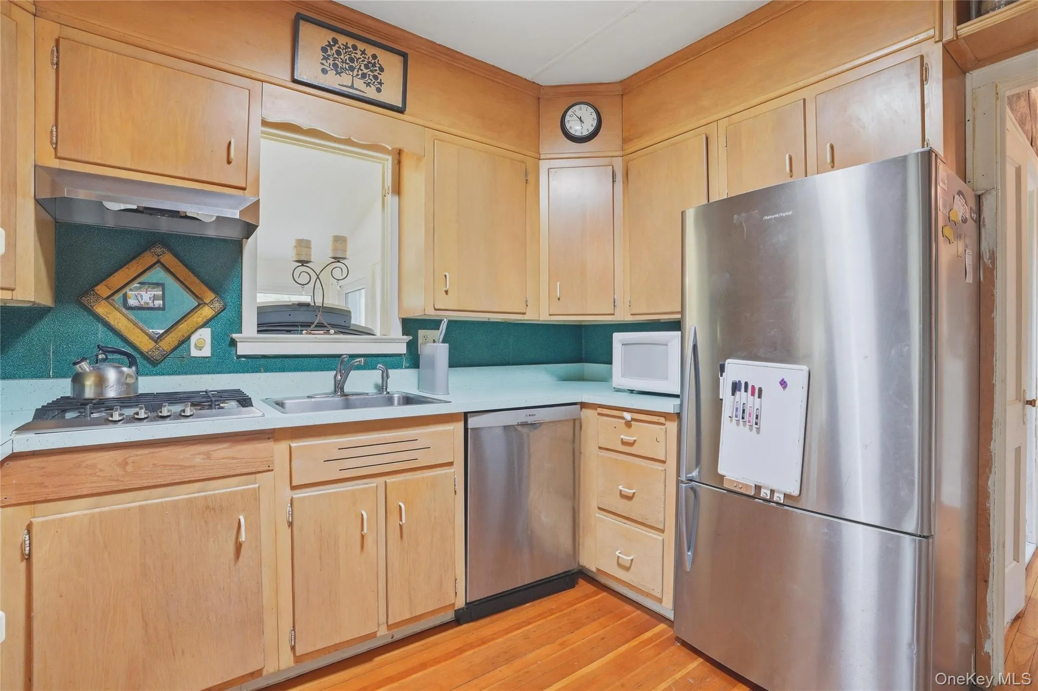 The kitchen features wood cabinetry, a stainless steel refrigerator, a stainless steel dishwasher, and a gas range The kitchen features wood cabinetry, a stainless steel refrigerator, a stainless steel dishwasher, and a gas range