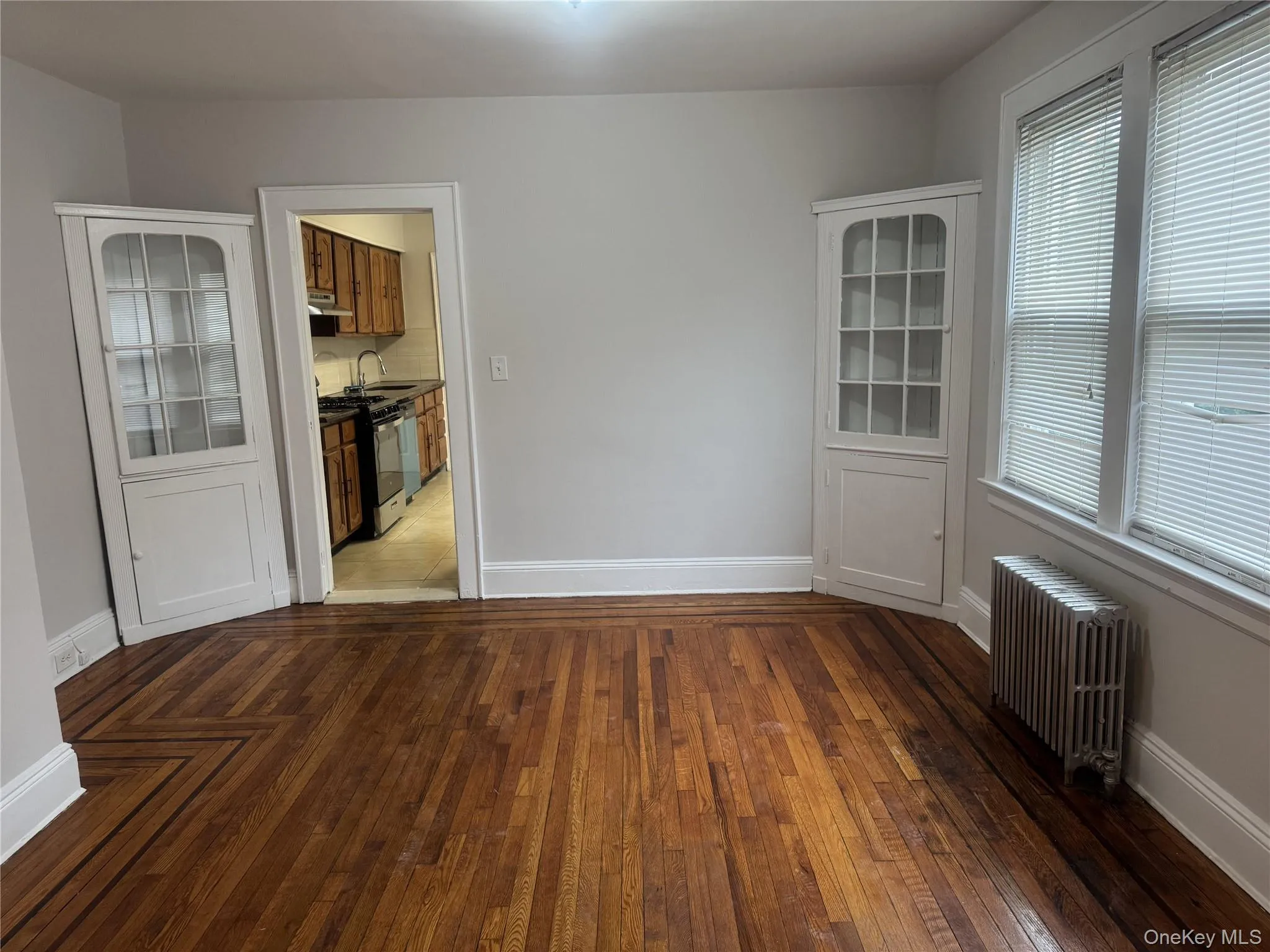 Empty room featuring radiator heating unit, dark wood-type flooring, and sink Empty room featuring radiator heating unit, dark wood-type flooring, and sink