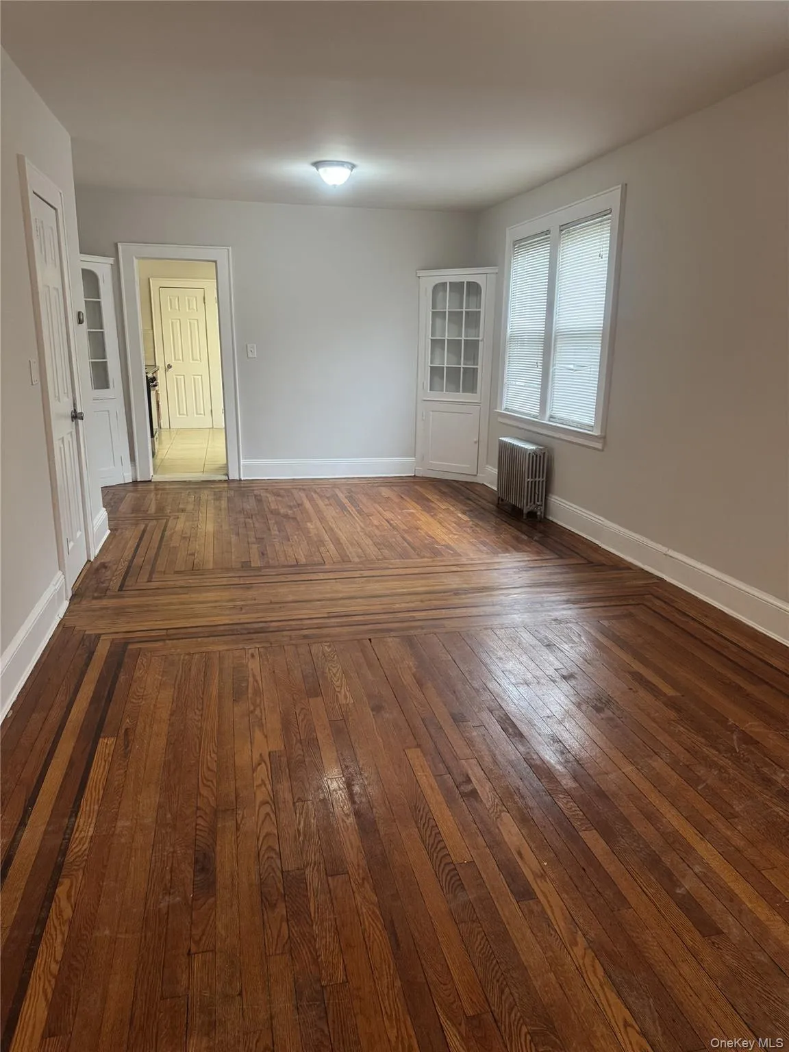 Unfurnished room with dark hardwood / wood-style flooring and radiator heating unit Unfurnished room with dark hardwood / wood-style flooring and radiator heating unit