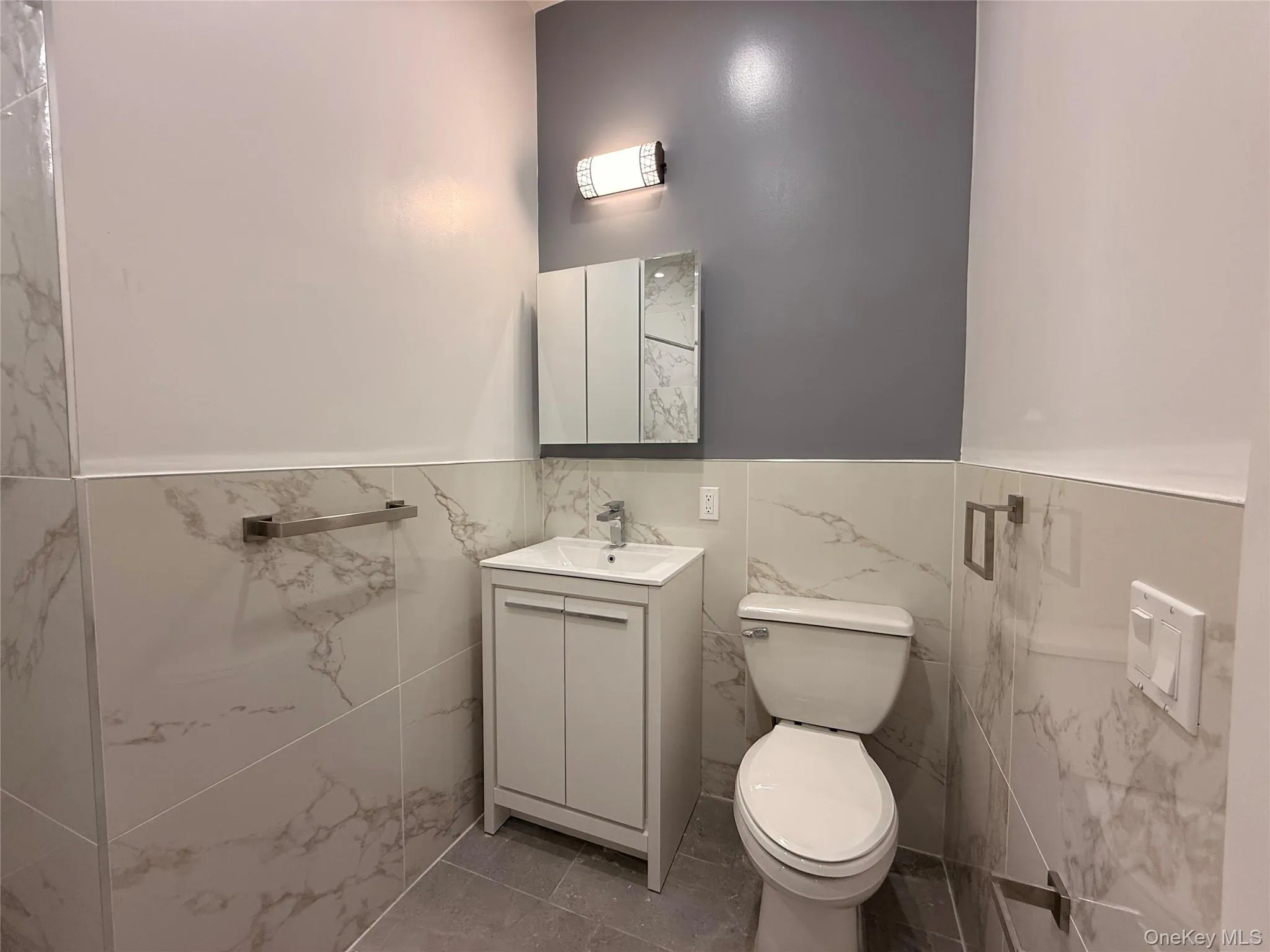 Bathroom featuring vanity, tile walls, and a wainscoted wall Bathroom featuring vanity, tile walls, and a wainscoted wall