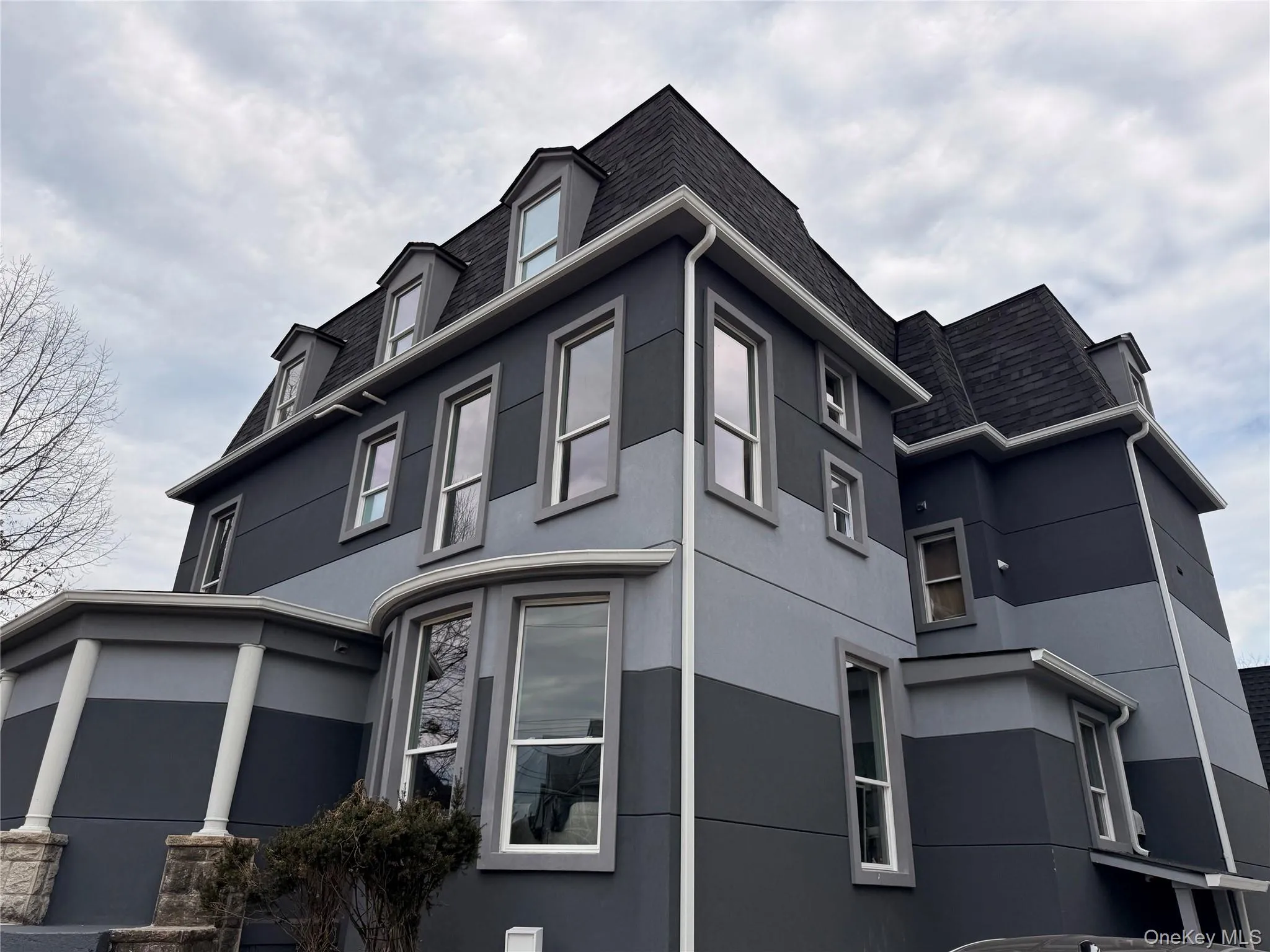View of property exterior featuring stucco siding, a shingled roof, and mansard roof View of property exterior featuring stucco siding, a shingled roof, and mansard roof