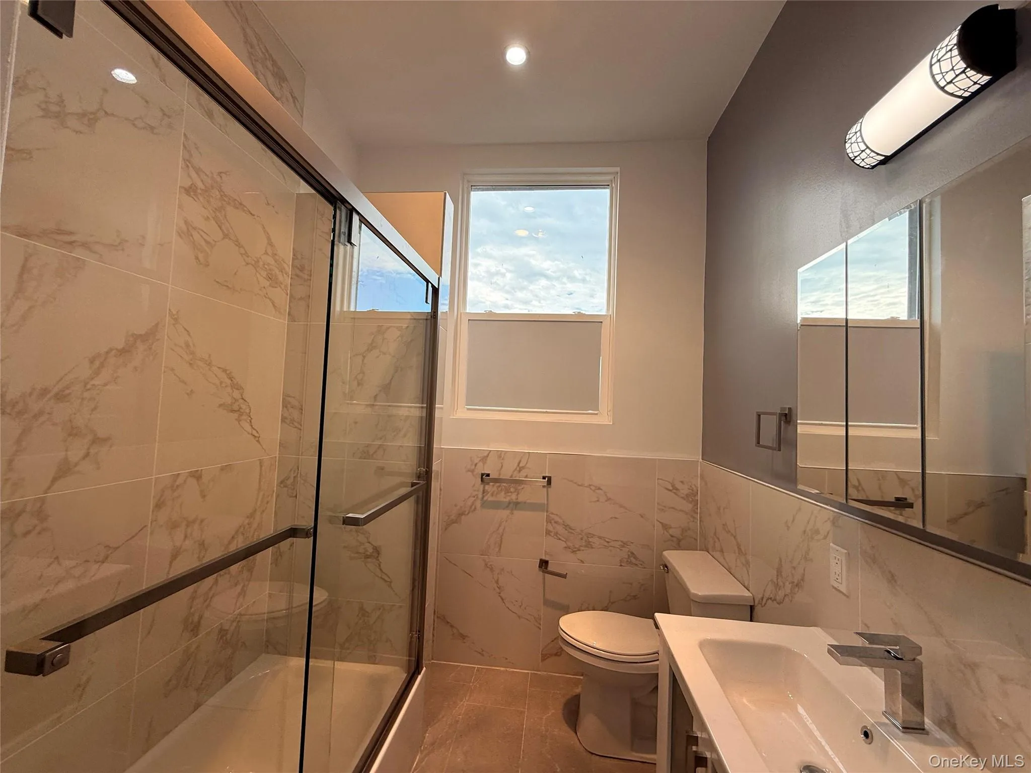 Full bath featuring tile walls, wainscoting, vanity, recessed lighting, and healthy amount of natural light Full bath featuring tile walls, wainscoting, vanity, recessed lighting, and healthy amount of natural light