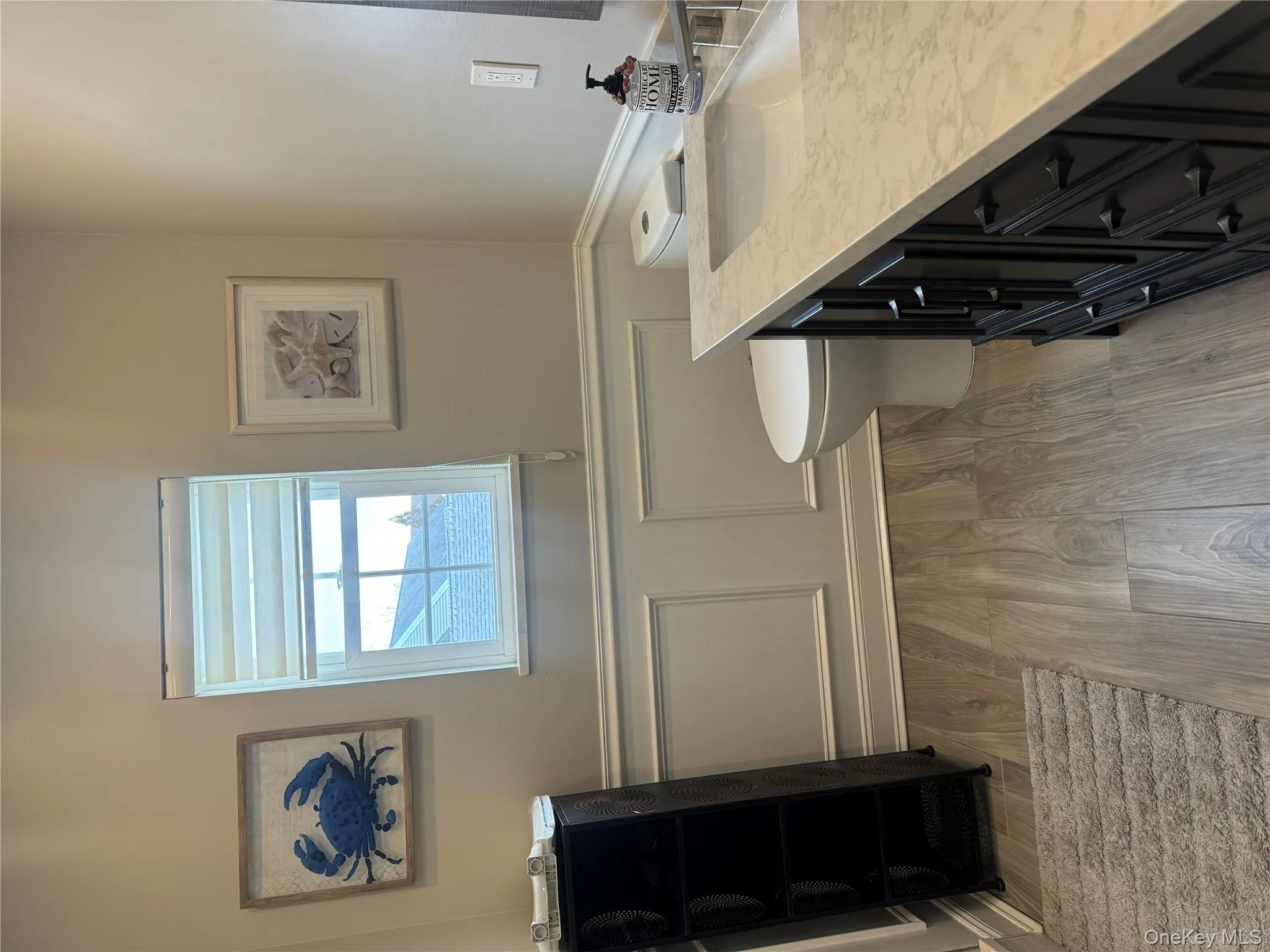 Bathroom with light wood-type flooring, vanity, wainscoting, and a decorative wall Bathroom with light wood-type flooring, vanity, wainscoting, and a decorative wall