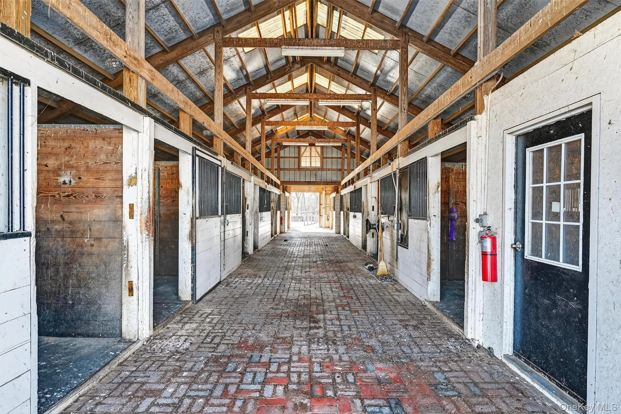 Brick aisleway of second barn. Matted stalls and spinning wall feeders. The heated office it to the right. Brick aisleway of second barn. Matted stalls and spinning wall feeders. The heated office it to the right.