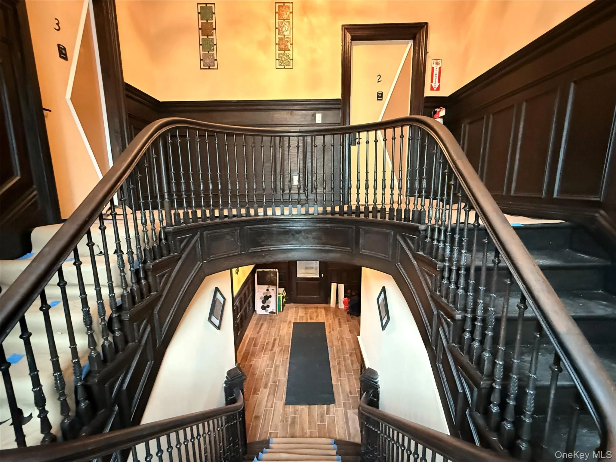 Stairway featuring a decorative wall, wood finished floors, and wainscoting Stairway featuring a decorative wall, wood finished floors, and wainscoting