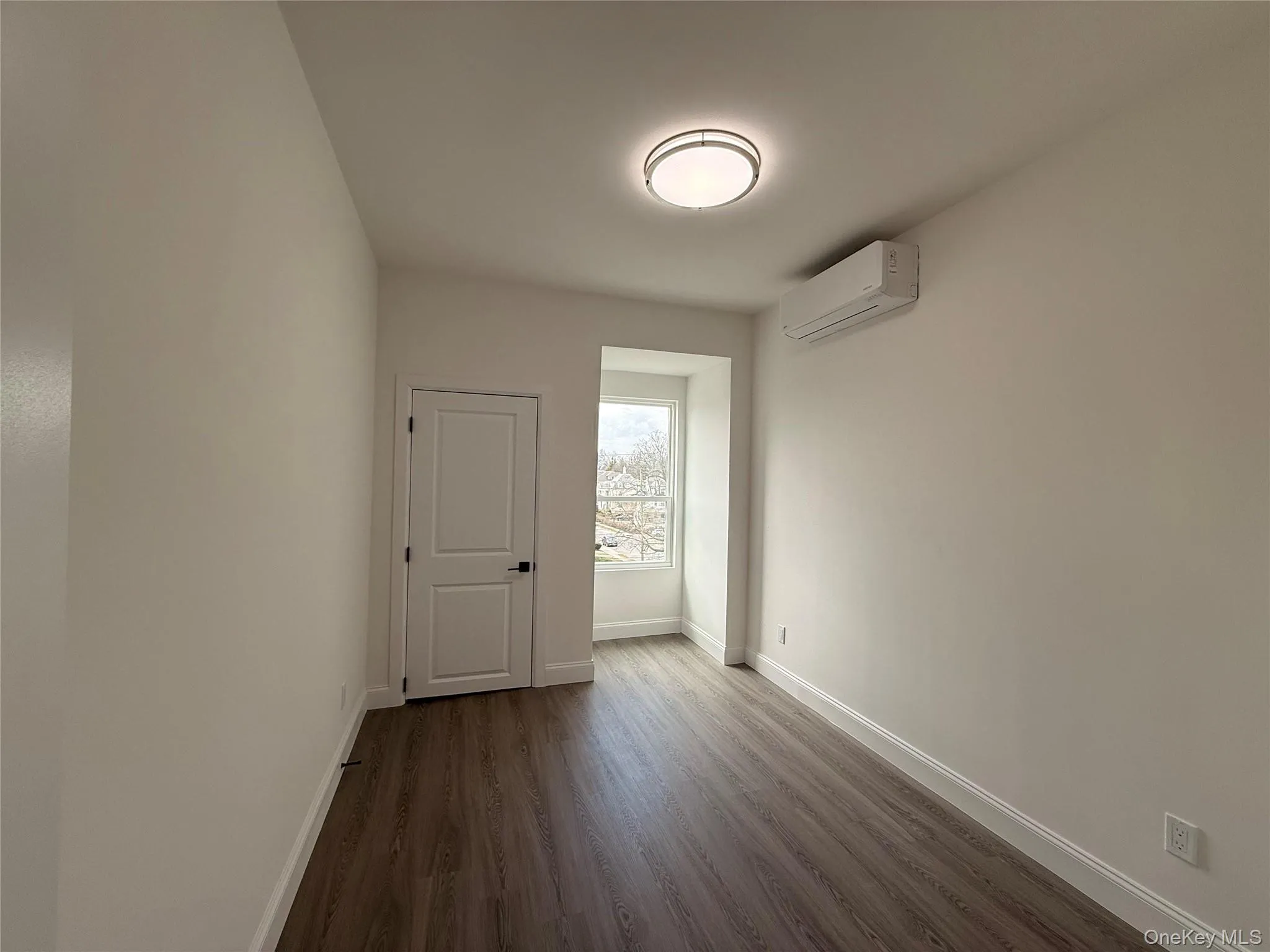 Bedroom #1 with dark wood-style floors and a mini split for heating / cooling Bedroom #1 with dark wood-style floors and a mini split for heating / cooling