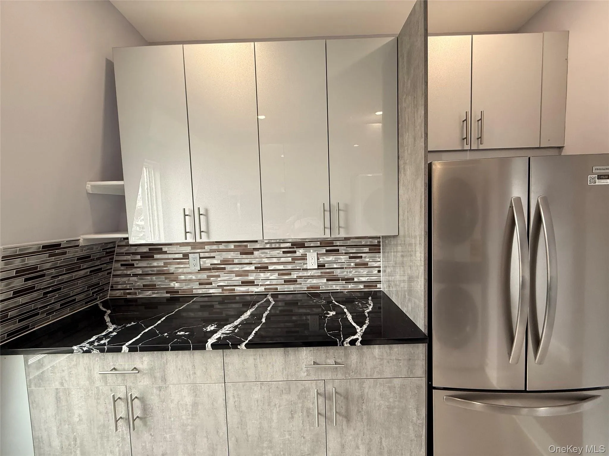 Kitchen featuring freestanding refrigerator, open shelves, tasteful backsplash, and dark stone counters Kitchen featuring freestanding refrigerator, open shelves, tasteful backsplash, and dark stone counters