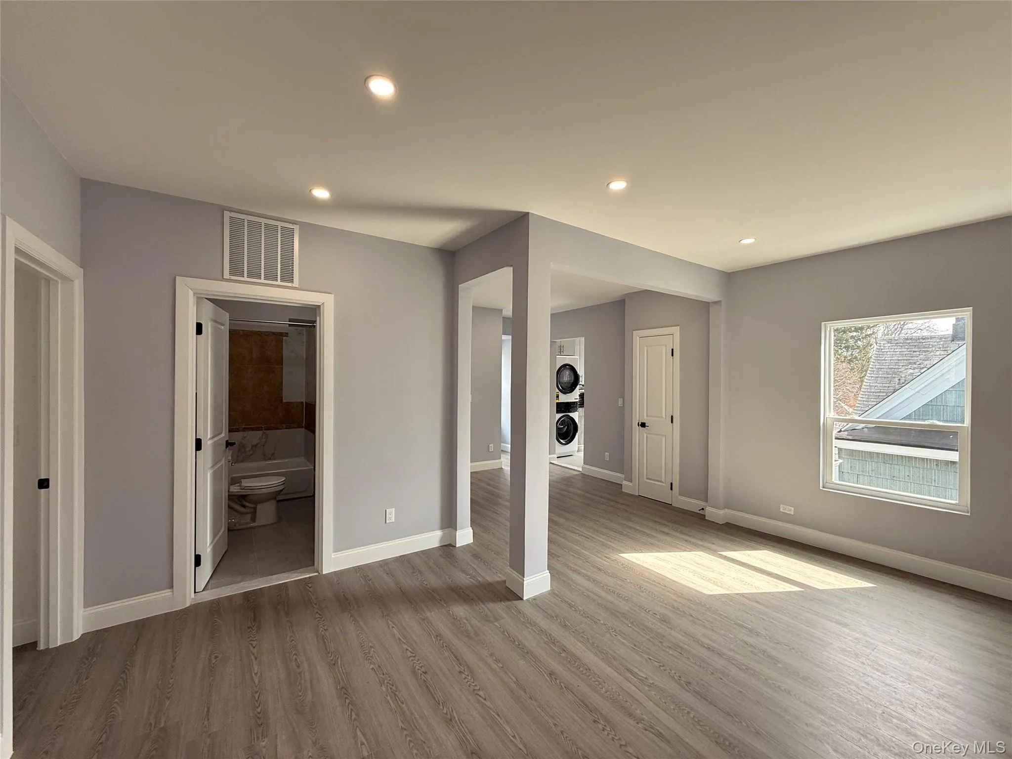 Living room with recessed lighting, light wood-style flooring, and stacked washer / dryer Living room with recessed lighting, light wood-style flooring, and stacked washer / dryer