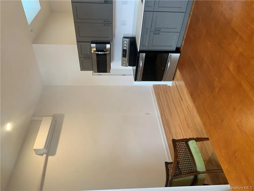 Kitchen featuring a wall unit AC, wood-type flooring, stove, and gray cabinetry Kitchen featuring a wall unit AC, wood-type flooring, stove, and gray cabinetry